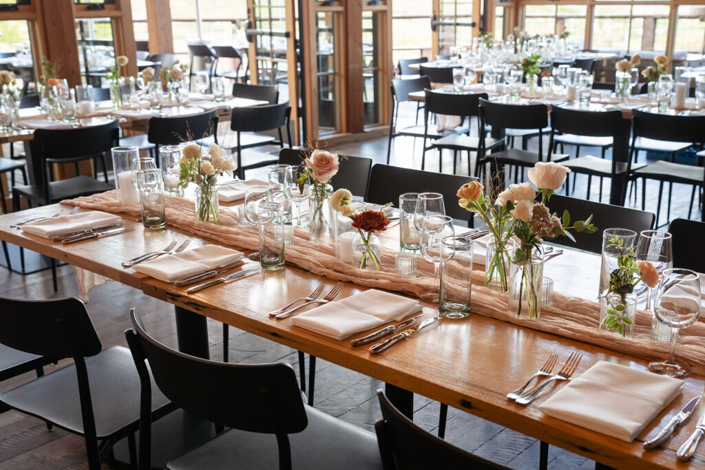 Long reception table with blush floral centerpieces, soft gauze runner, modern place settings, and glassware at a luxury destination wedding at High West Distillery in Park City, Utah, planned by Shellie Ferrer Events.