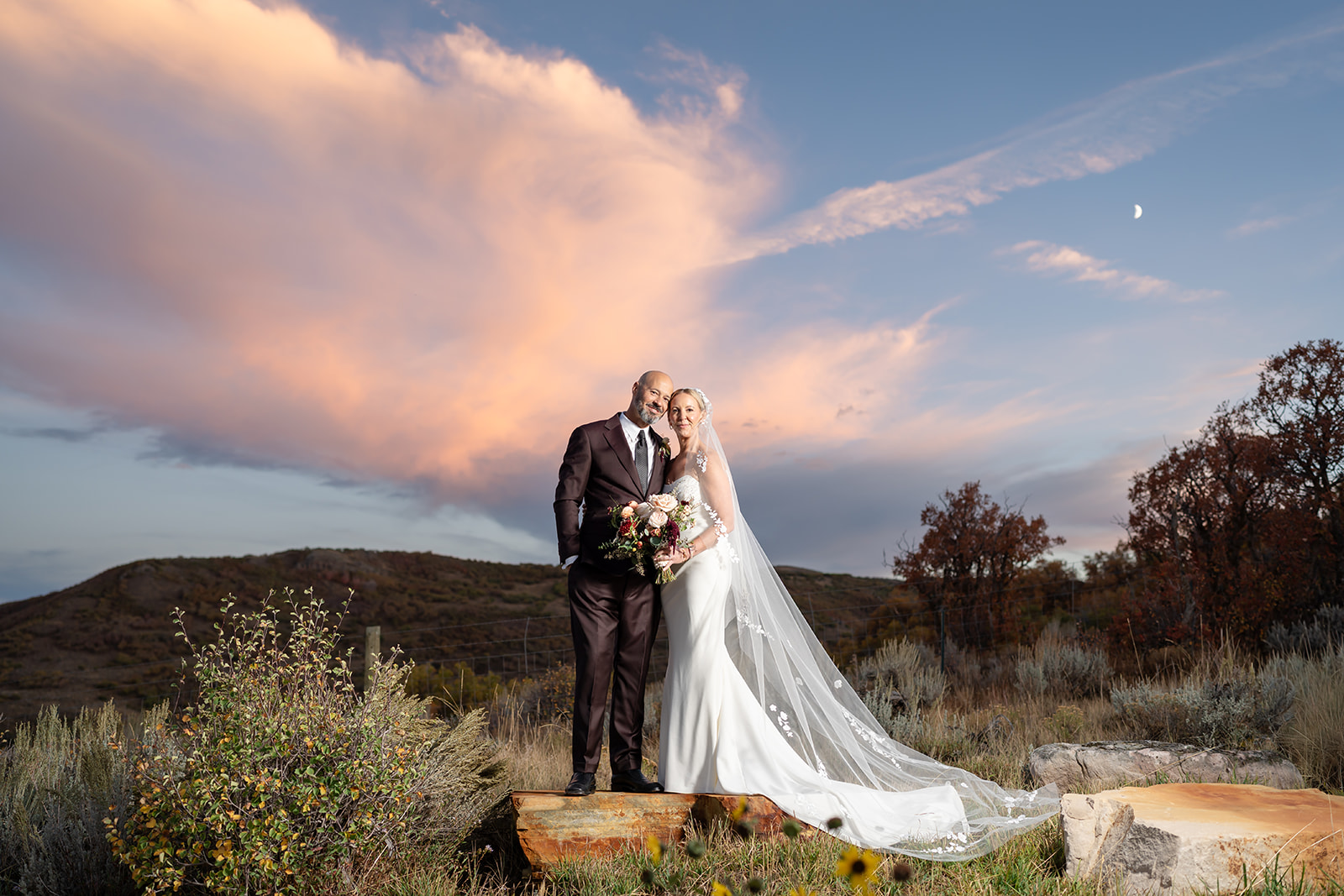 Bride and groom posing at sunset with dramatic clouds and mountain scenery at High West Distillery in Park City, Utah, during a luxury destination wedding planned by Shellie Ferrer Events.
