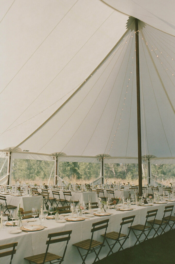 Elegant sailcloth wedding tent reception with long banquet tables, candlelight, and minimalist floral centerpieces at a private residence on Wolfe Creek Ranch Road in Utah, planned by Shellie Ferrer Events.
