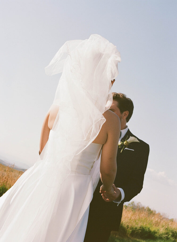 Bride in a flowing veil holding hands with the groom during a destination luxury wedding portrait at a private residence on Wolfe Creek Ranch Road in Utah, planned by Shellie Ferrer Events.