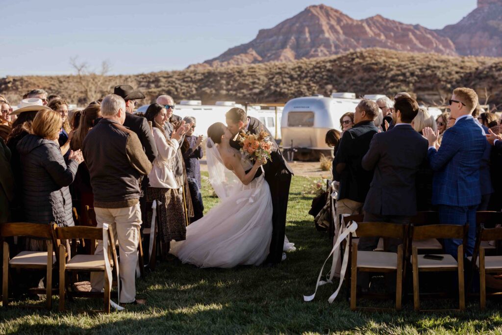 Wedding photo of a bride and groom kissing in the aisle at AutoCamp Zion in Utah near Zion National Park.