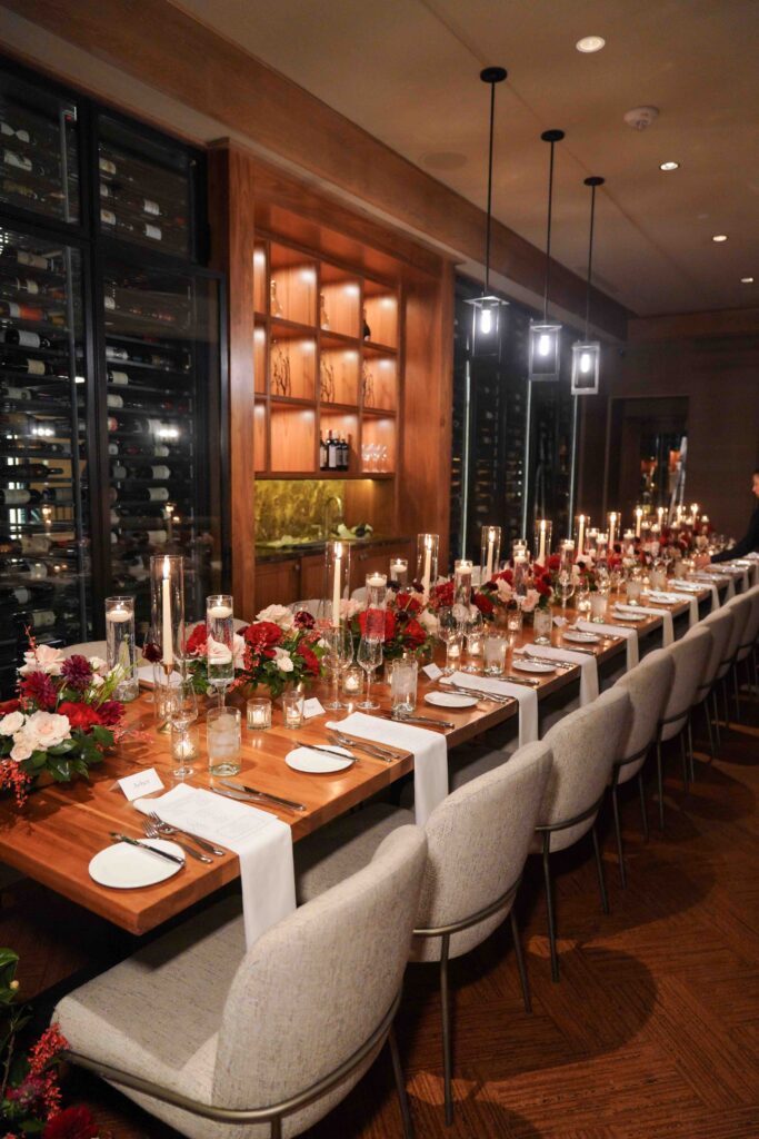 Intimate wedding dinner reception in the St. Regis Deer Valley wine cellar featuring candlelit tables, red and ivory floral arrangements, and elegant guest seating in Park City, Utah, planned by Shellie Ferrer Events.