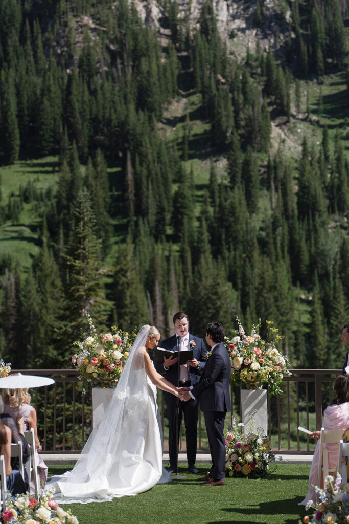 Bride and groom holding hands during their outdoor wedding ceremony at Snowpine Lodge in Little Cottonwood Canyon, Utah.