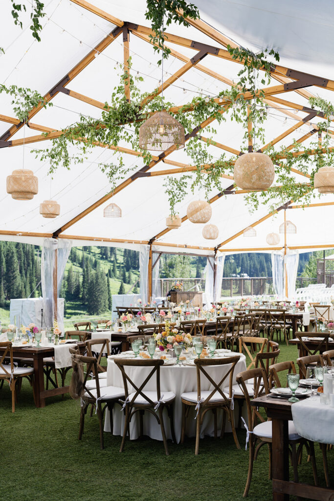 Elegant tented wedding reception with greenery, woven pendant lights and colorful florals at Snowpine Lodge in Little Cottonwood Canyon, Utah.