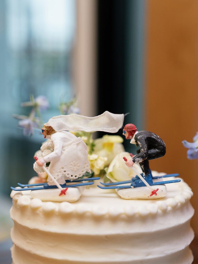 Vintage bride and groom ski cake topper displayed on a white wedding cake at Snowpine Lodge in Little Cottonwood Canyon, Utah.