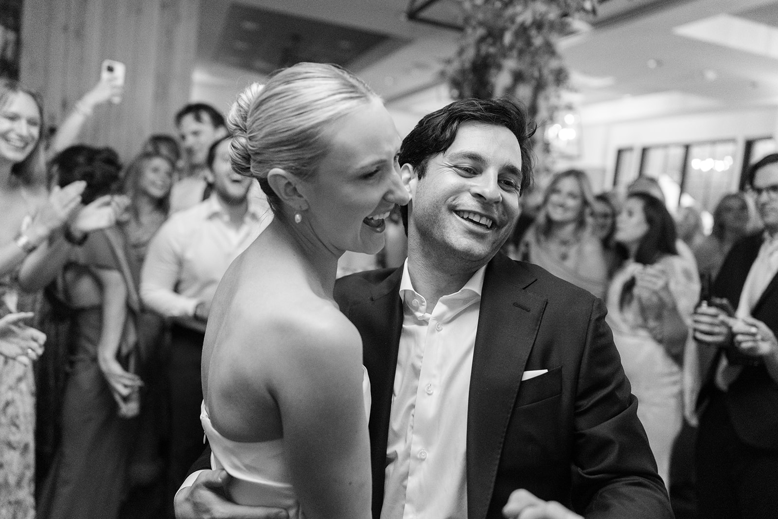 Black-and-white photograph of the bride and groom laughing together on the dance floor during their Snowpine Lodge wedding reception.