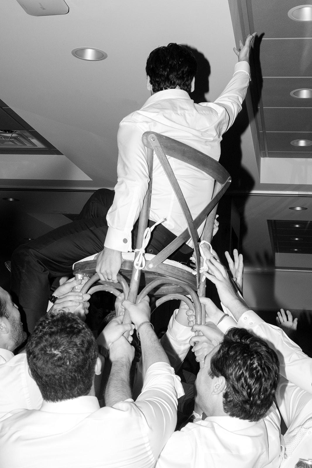Black-and-white photograph of the groom being lifted in a chair during the hora at a Snowpine Lodge wedding reception in Utah.